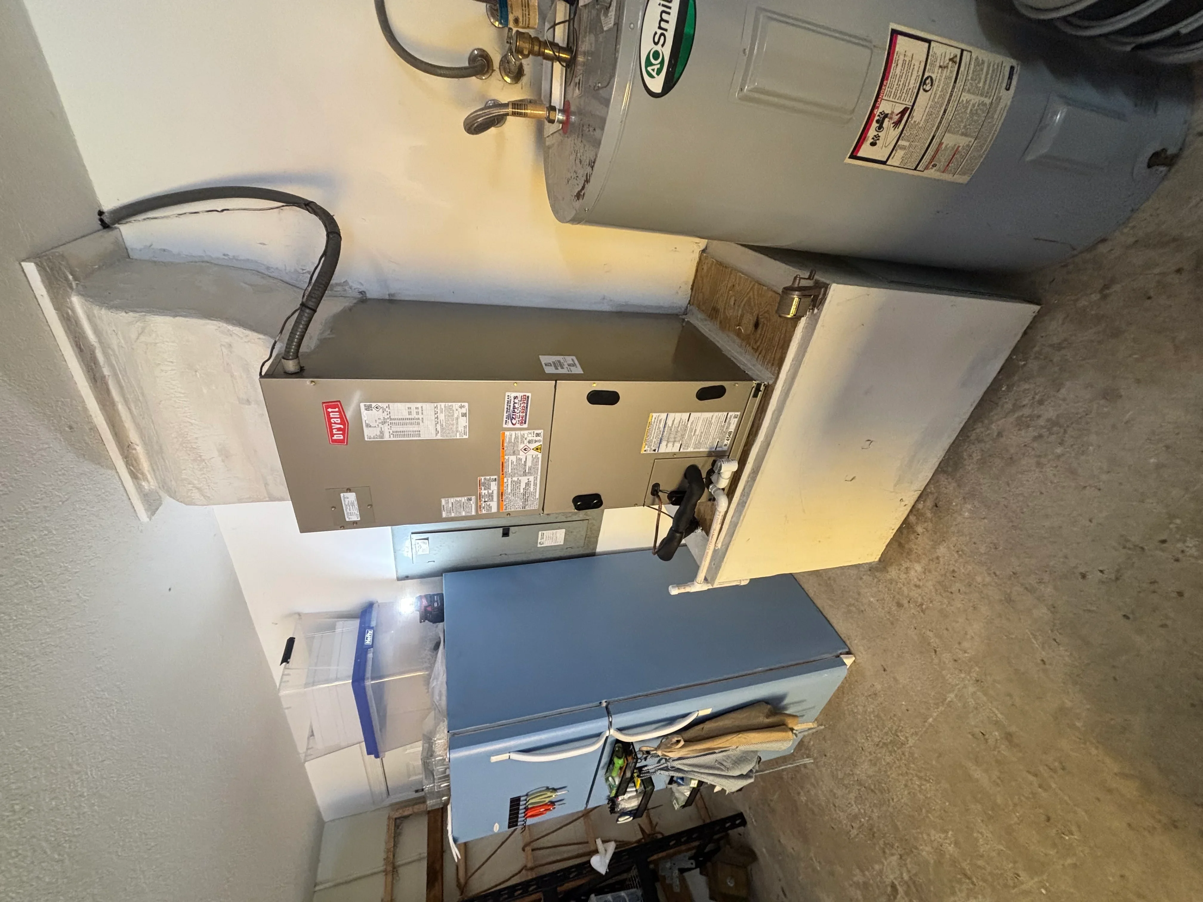 Installed furnace unit with water heater, ductwork, and electrical connections in utility room